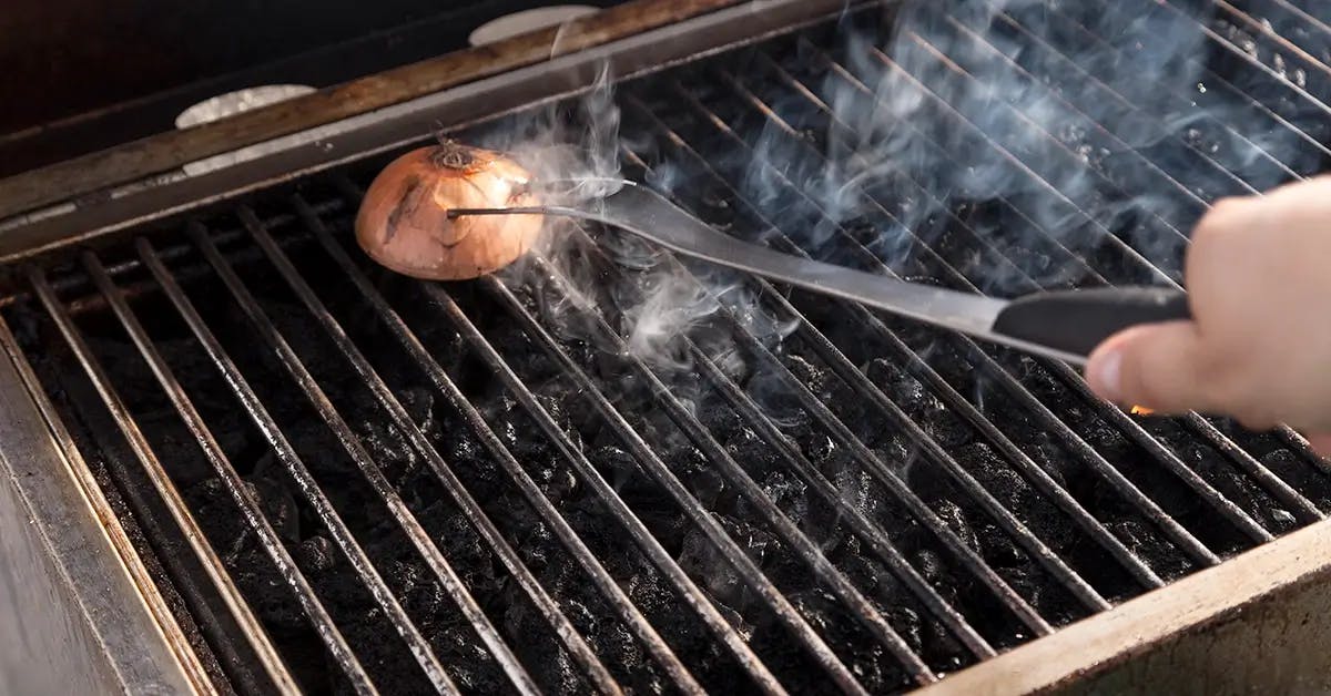 Cleaning a barbecue grill with an onion.