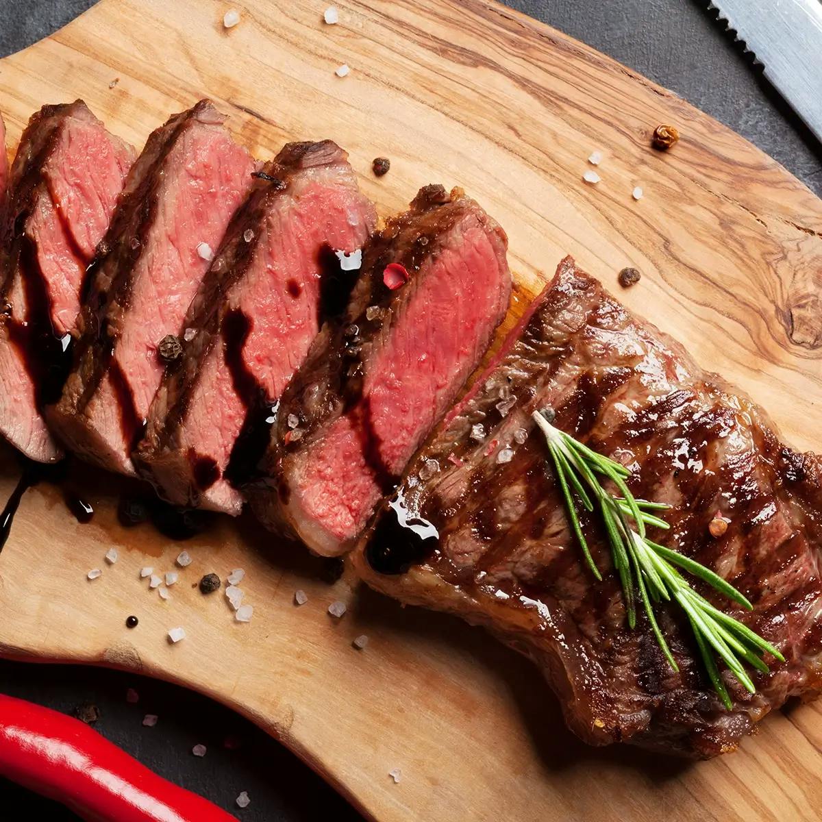 Sliced meat resting on a cutting board after barbecuing.