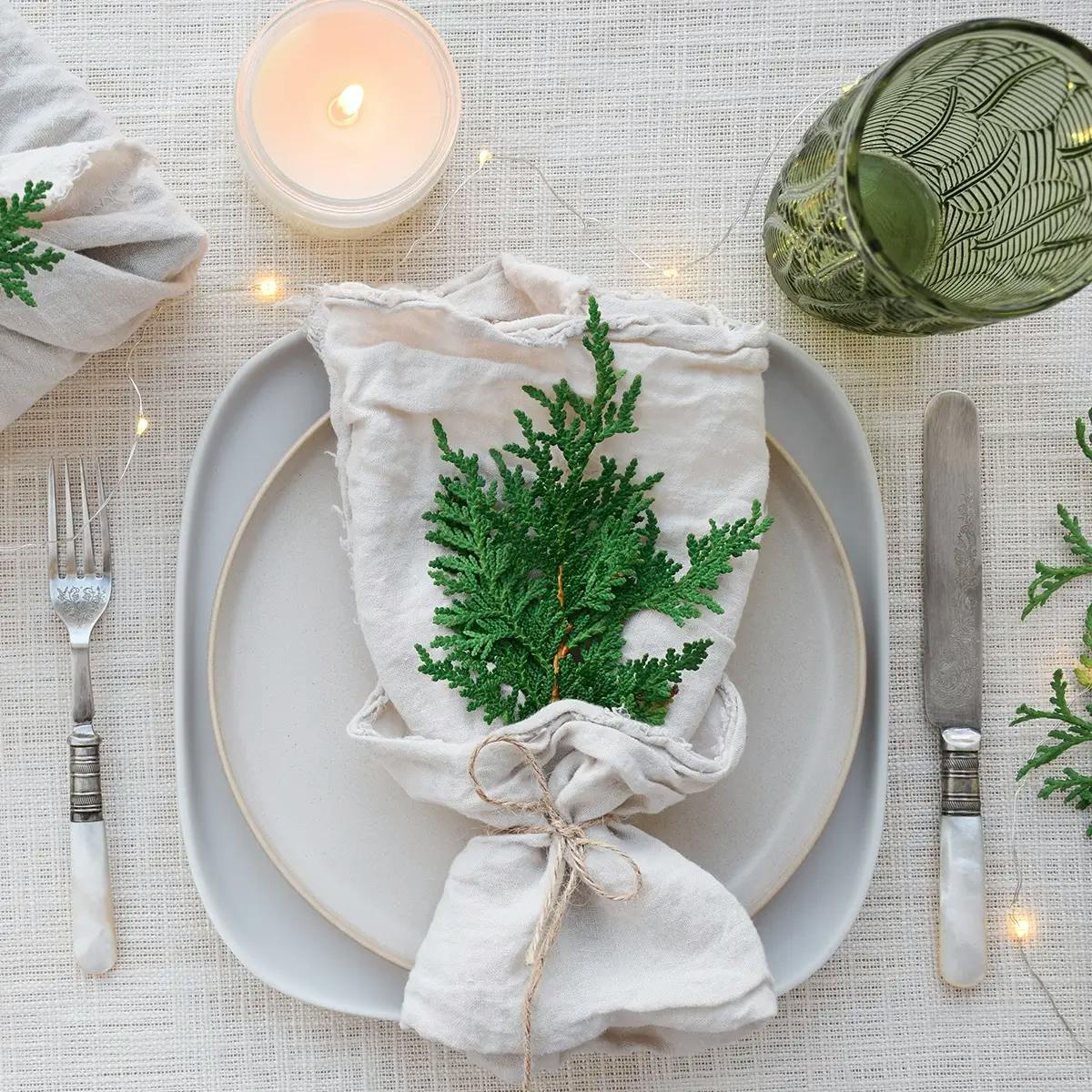 Eco-friendly holiday table setting with cloth napkin, cloth-wrapped gift, and pine decorations.
