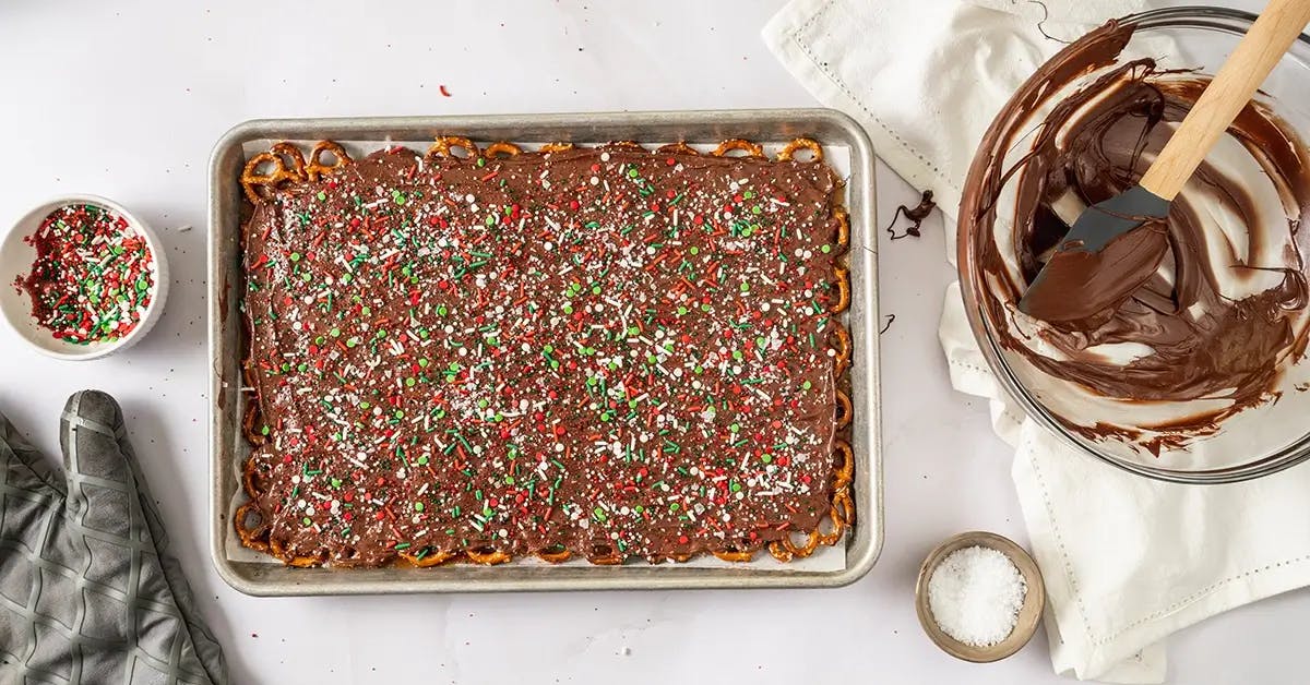 A tray of Christmas Crack with Pretzels, covered in sprinkles and left to cool.