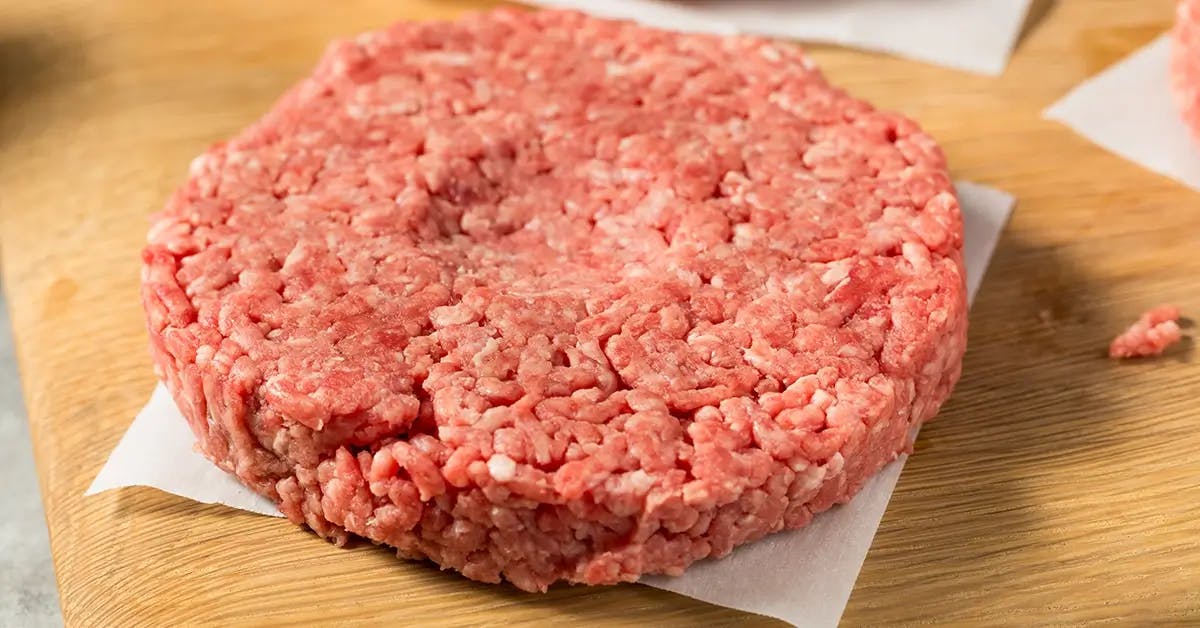 Raw burger with a dimple in the center to cook evenly.