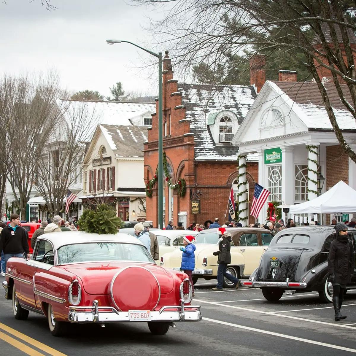 Vintage cars parked on a snowy street in Stockbridge, MA, as they prepare to create the famous Norman Rockwell painting.