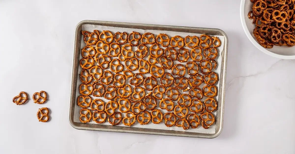 Adding pretzels to a baking sheet ready to make a Christmas Crack recipe.