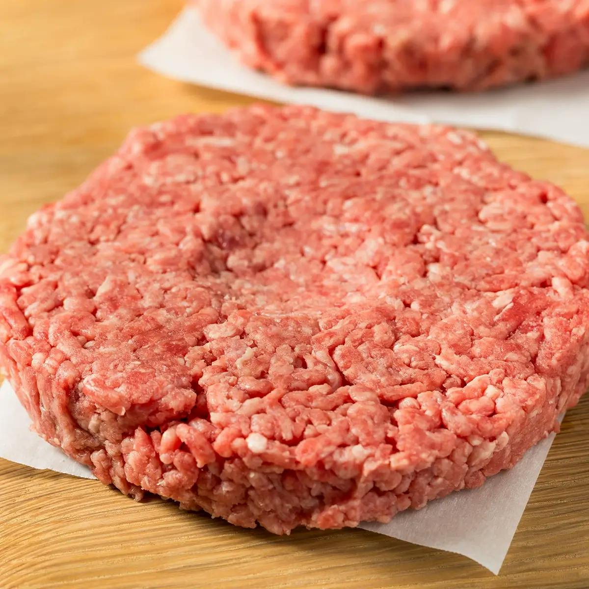 Raw burger with a dimple in the center to cook evenly.