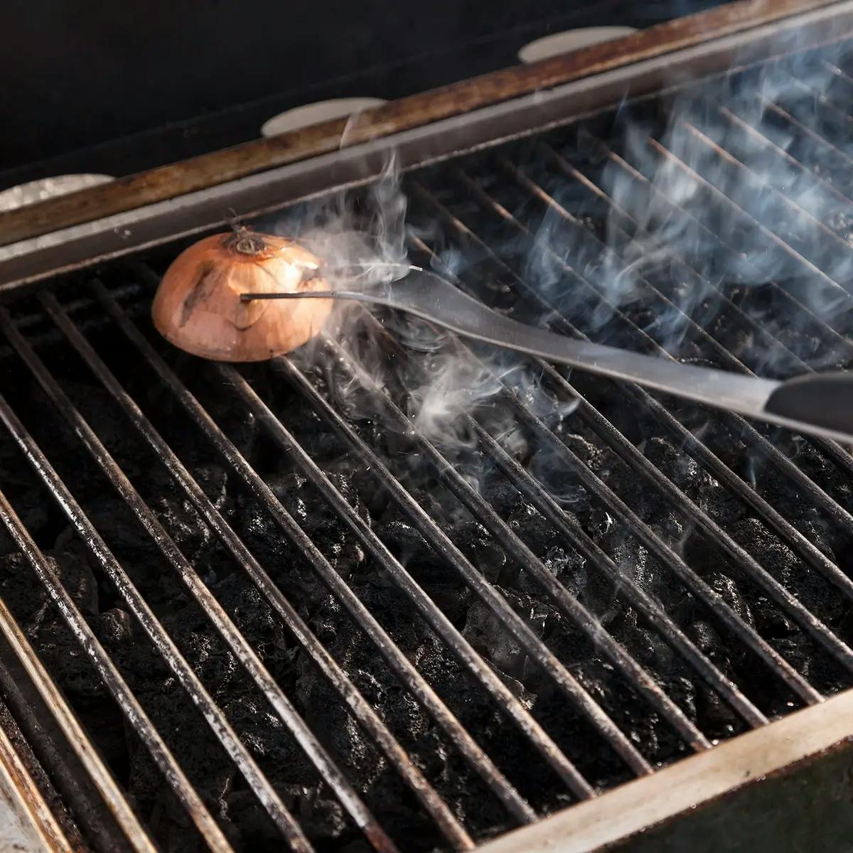 Cleaning a barbecue grill with an onion.